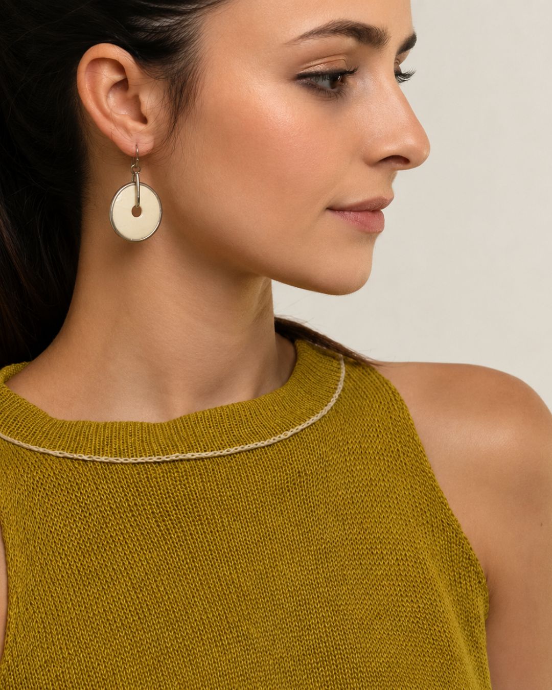 Side profile of model wearing lightweight handcrafted ostrich eggshell disc earrings made from natural materials.