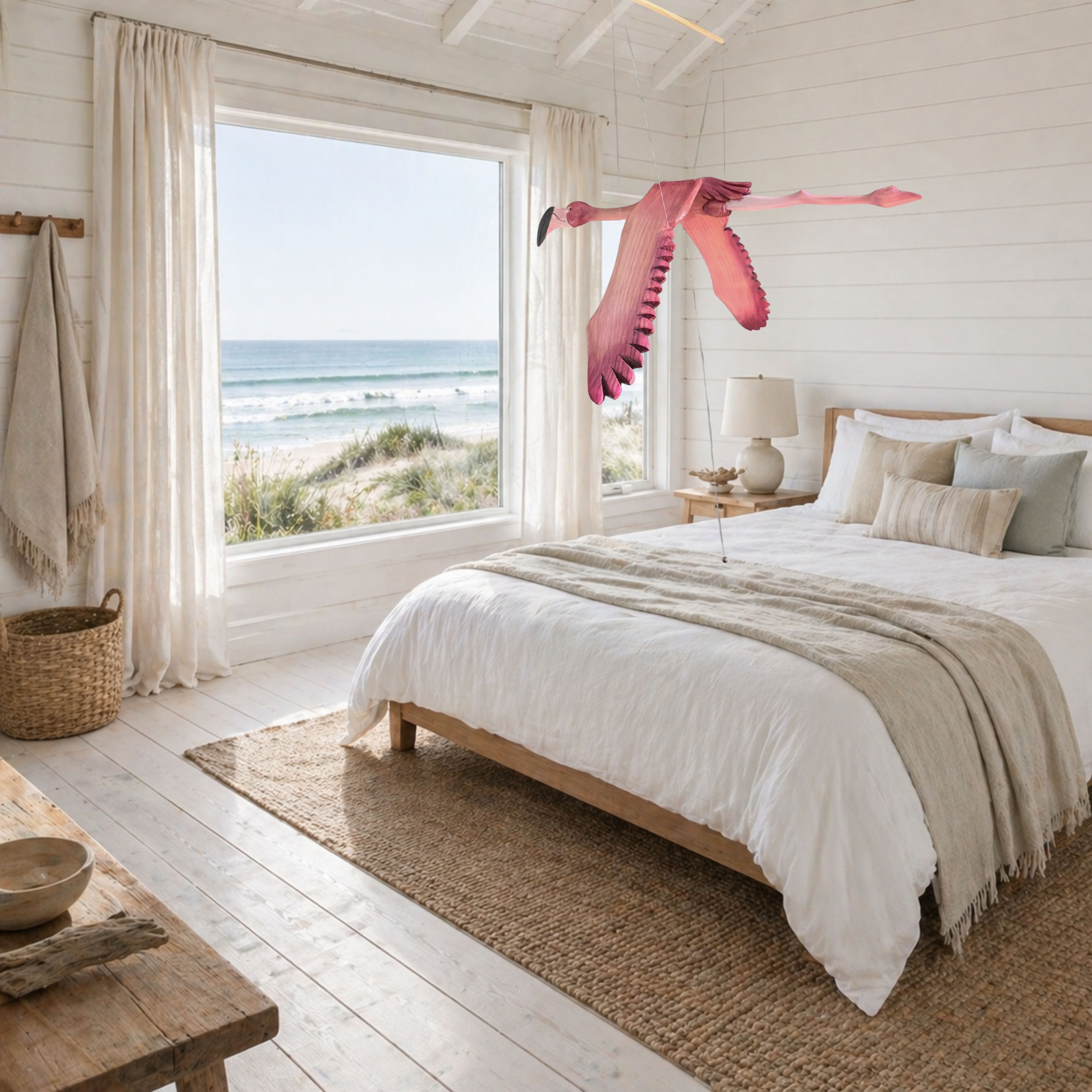 A hand-carved wooden flamingo mobile in flight in a Beach-themed bedroom with ocean view