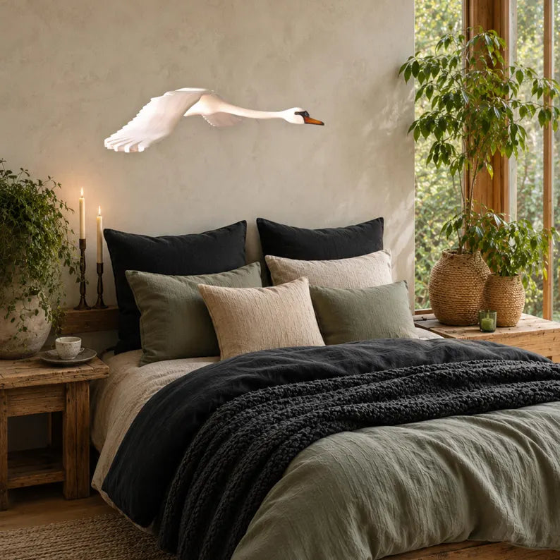 Hand-carved wooden swan mobile in flight above a bed in a warm, nature-inspired bedroom