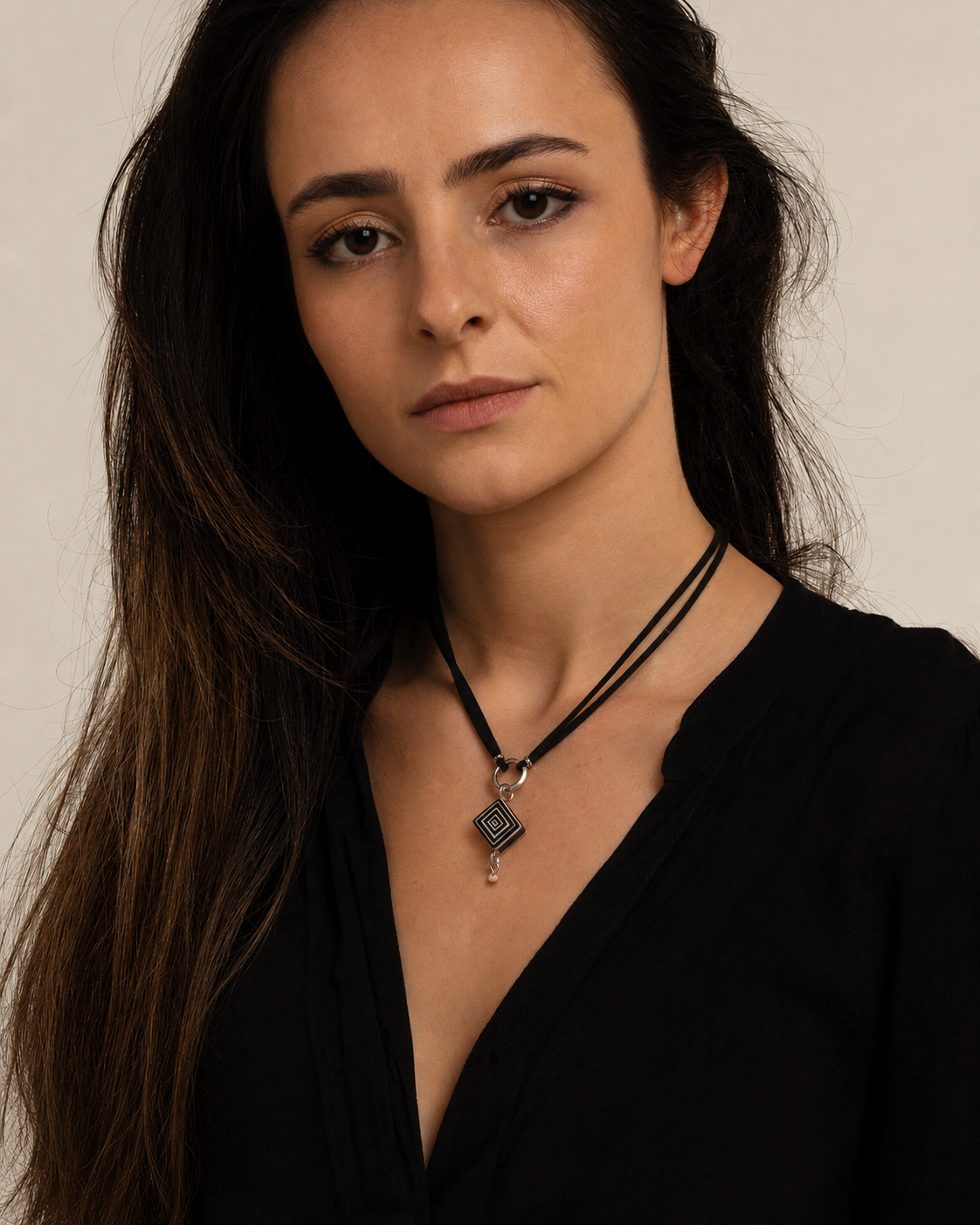 Woman wearing a handcrafted petite geometric ostrich eggshell necklace with a layered diamond-shaped pendant and black suede cord.