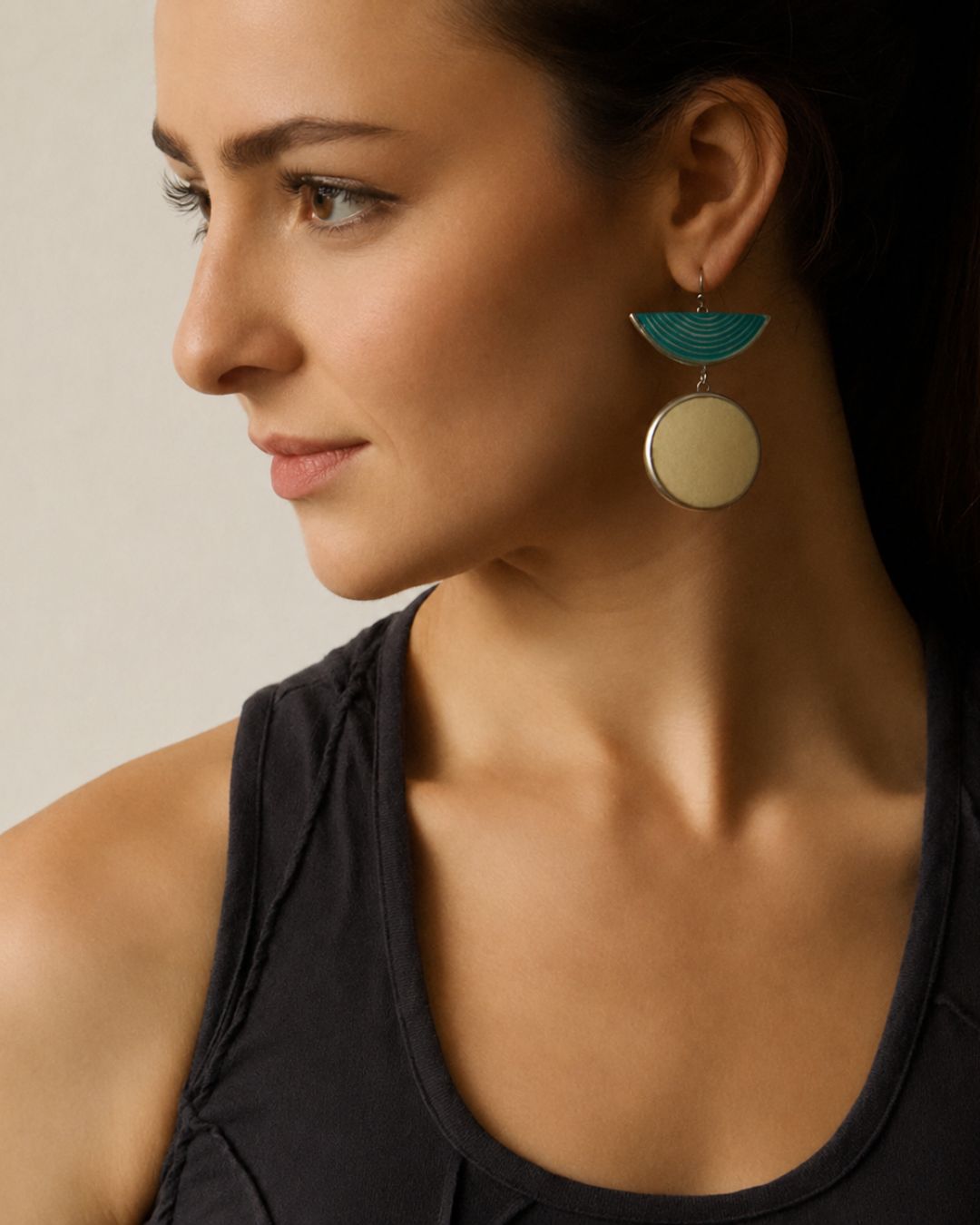 Woman wearing contemporary artisan turquoise half moon ostrich eggshell earrings with a black top.