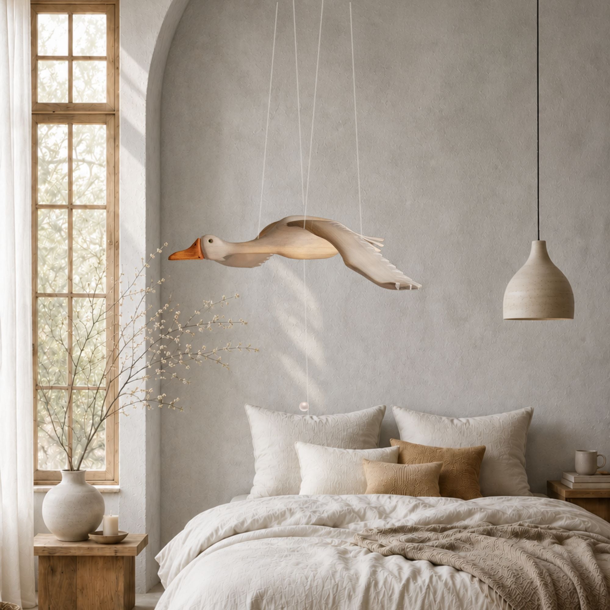 a wooden hand carved grey goose mobile hanging above a bed in a Scandinavian bedroom