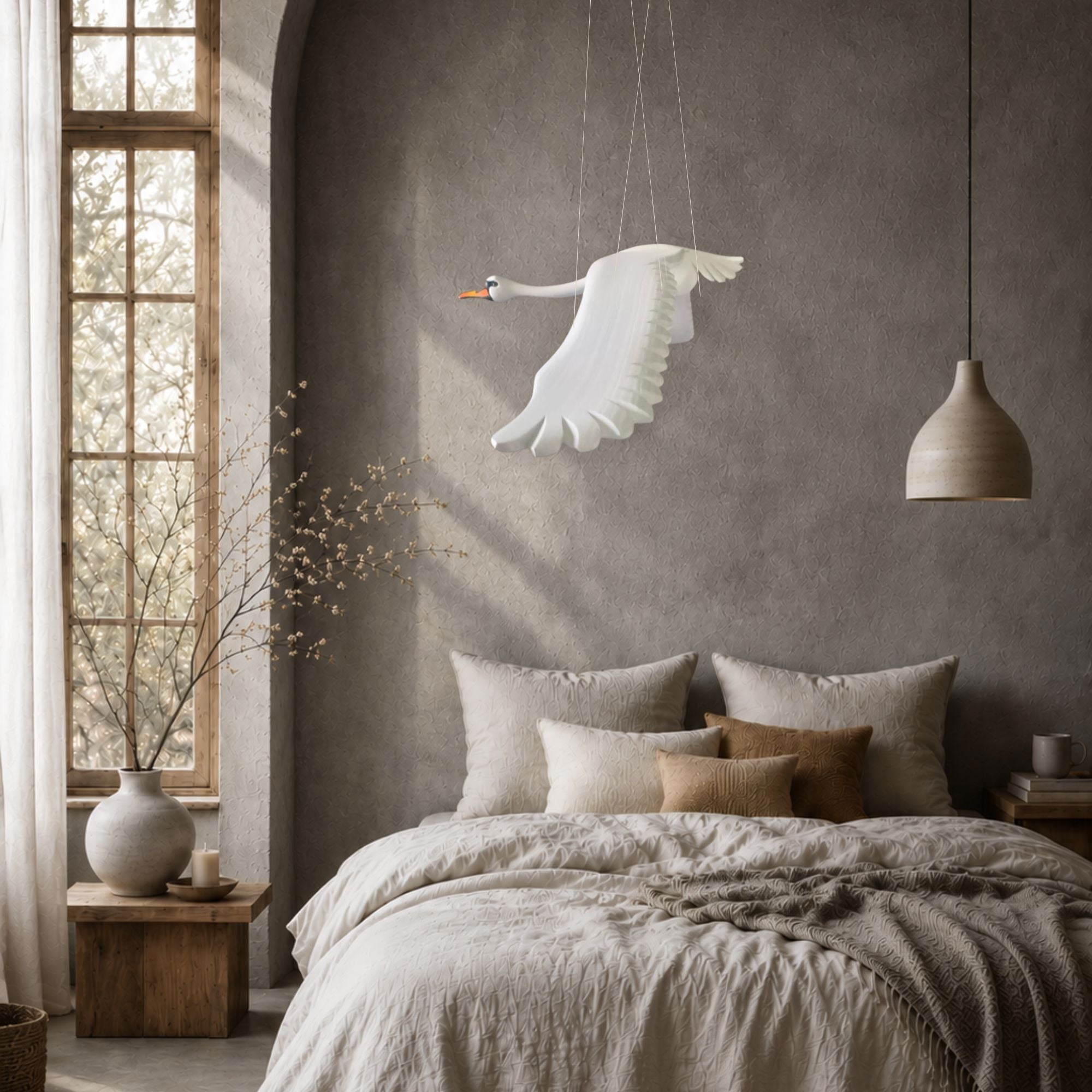 Hand-carved wooden swan mobile in flight above a bed in a light Scandinavian-style bedroom