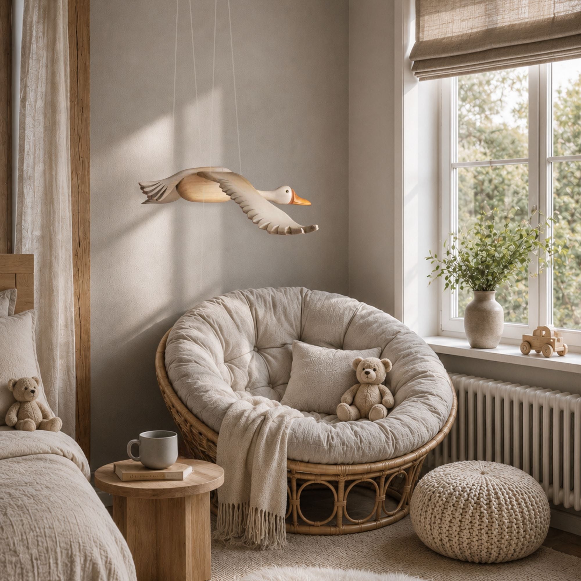 Handmade wooden grey goose mobile hanging in a cozy nursery with a papasan chair and teddy bear