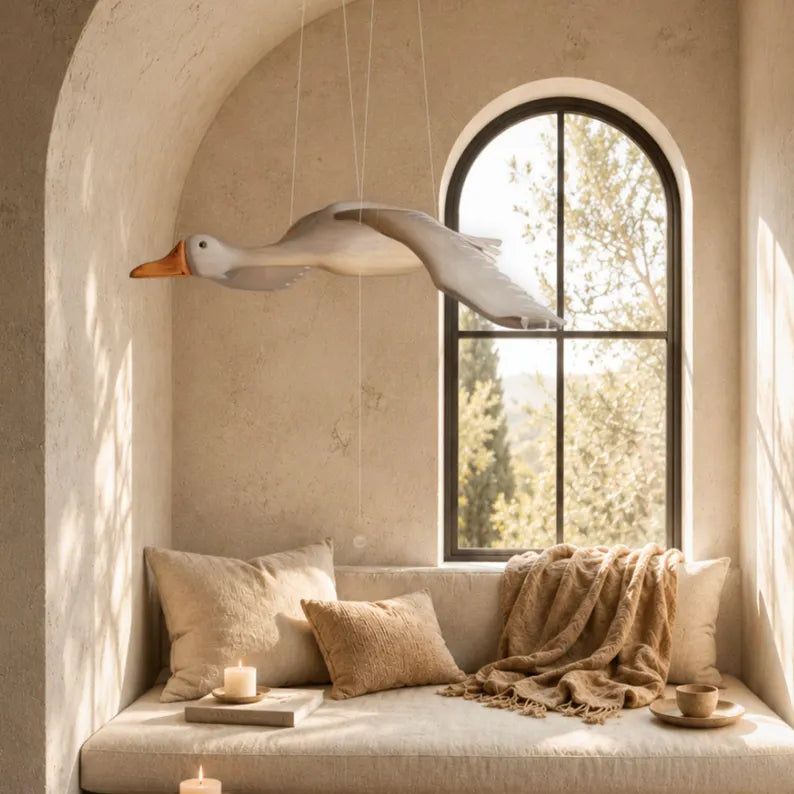 Decorative flying Goose mobile above a cozy sitting area with pillows and a blanket