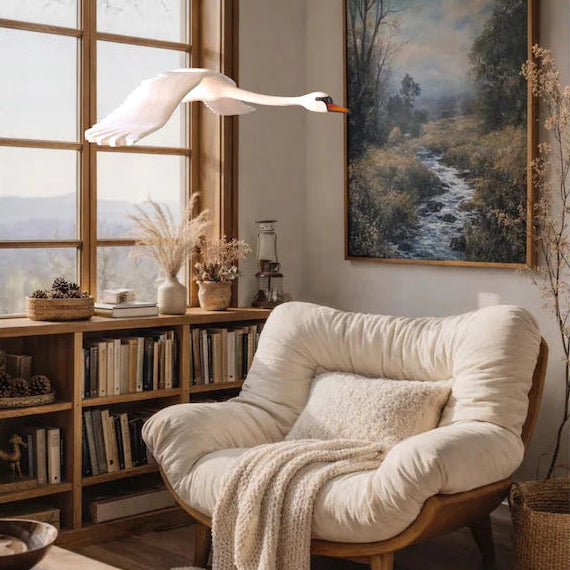A hand-carved wooden swan mobile in a cozy reading nook by a window