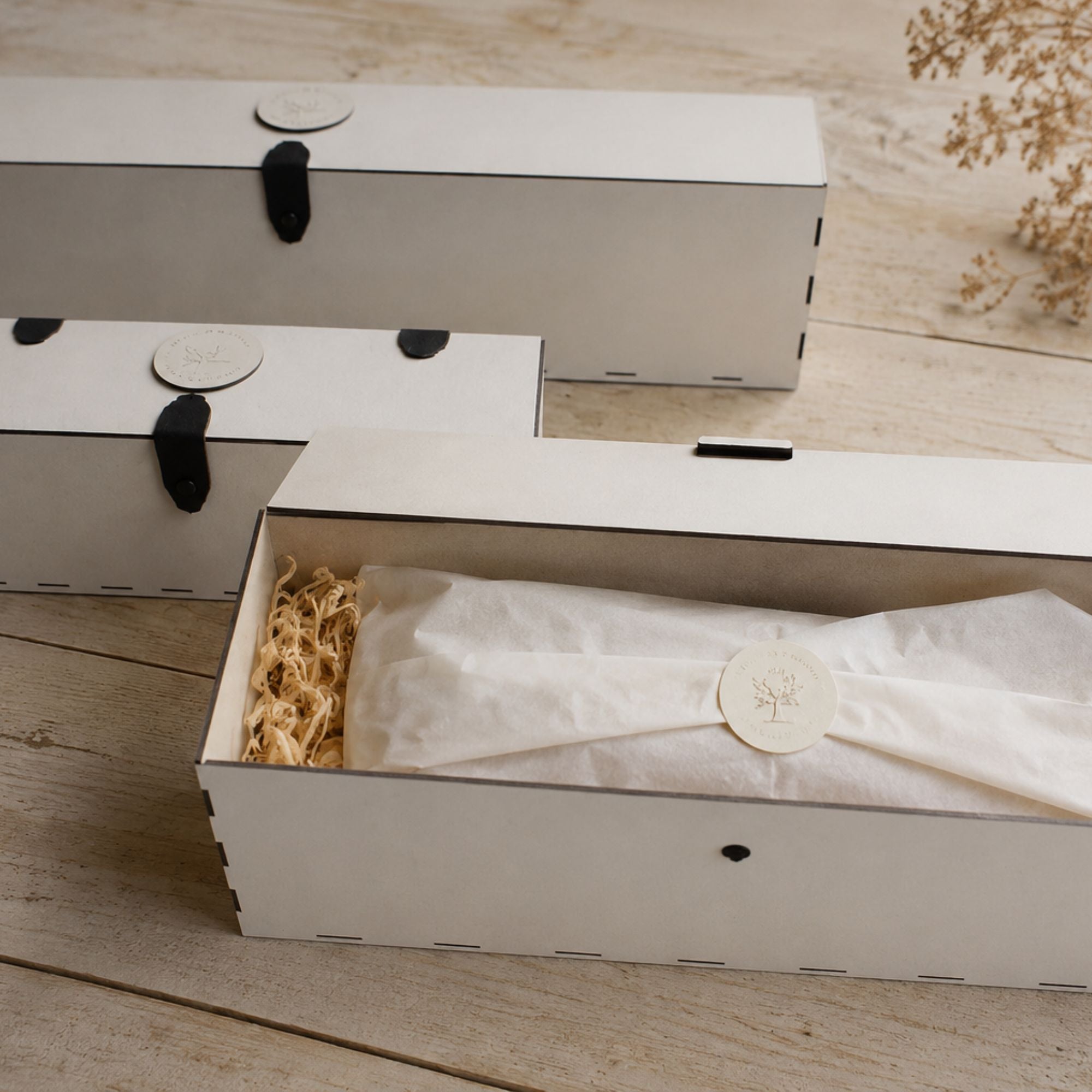 White wooden gift  box with leather hinges on a wooden surface showing gift packaging for a hand carved mobile wooden bird