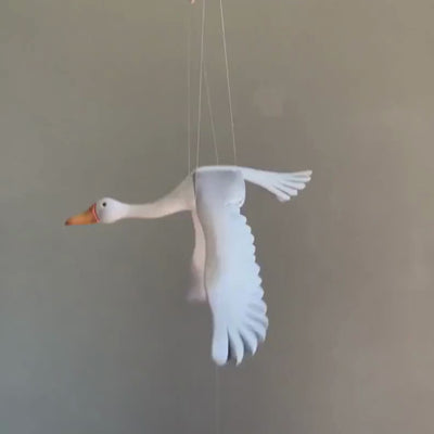 A hand carved wooden goose mobile in graceful flight